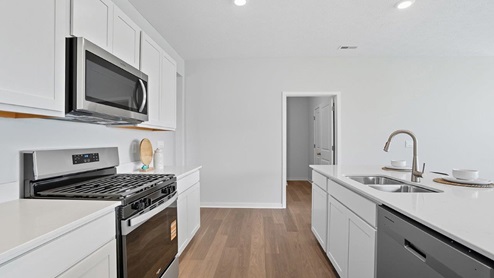 kitchen with white cabinets, hard surface appliances and built in island