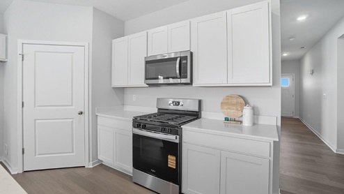 kitchen with white cabinets, stainless steel appliances, corner walk in pantry