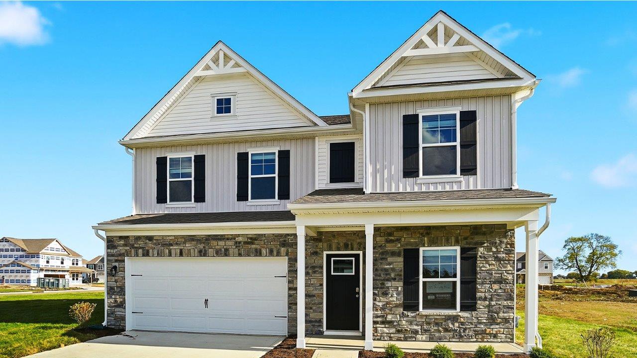 two story home with white siding, partial stone front, covered patio and two car garage