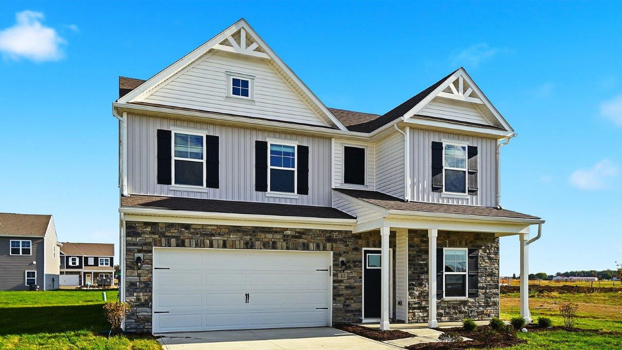 two story home with white siding, partial stone front, covered patio and two car garage
