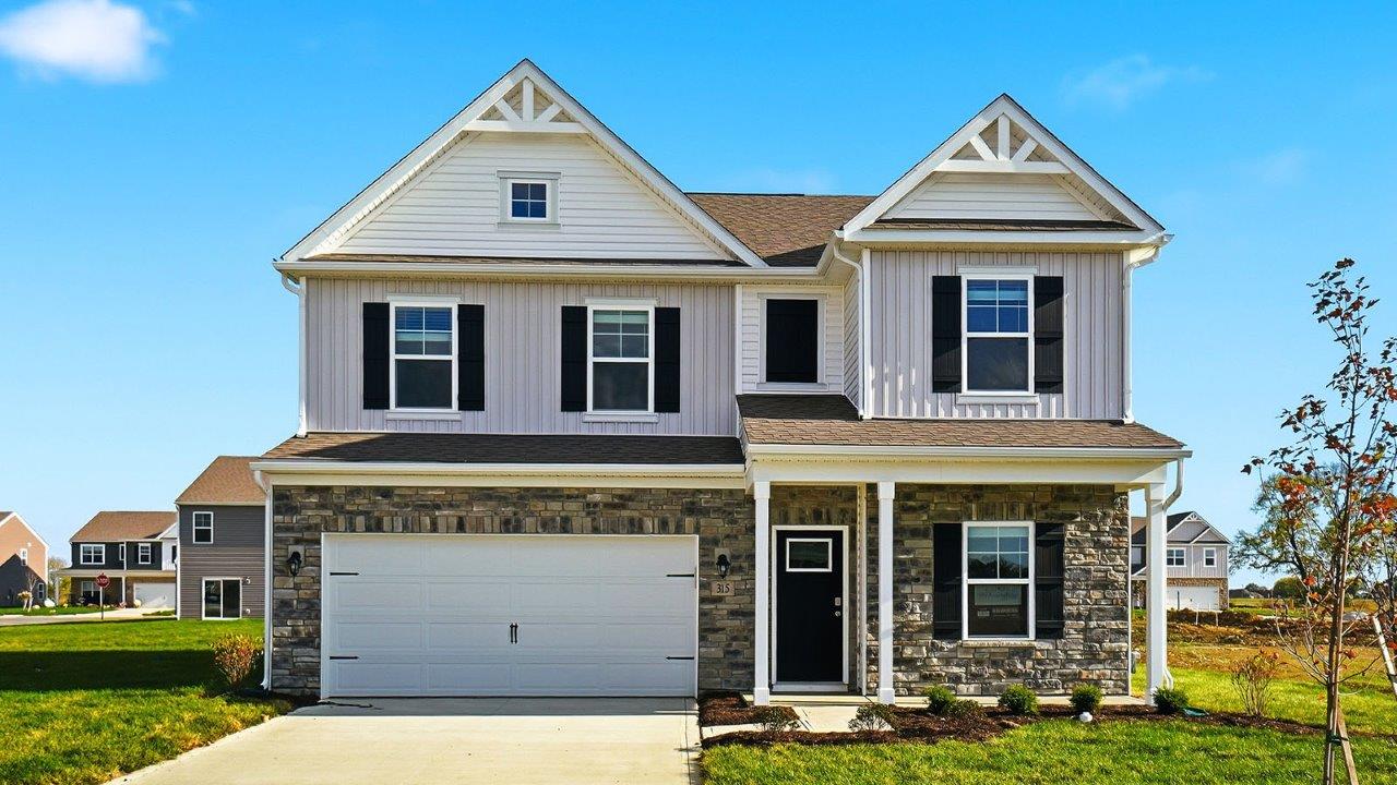 two story home with white siding, partial stone front, covered patio and two car garage