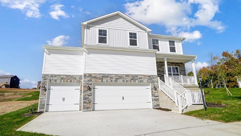 two story home with white siding, steps with railing to covered front porch, three car garage, partial stone front