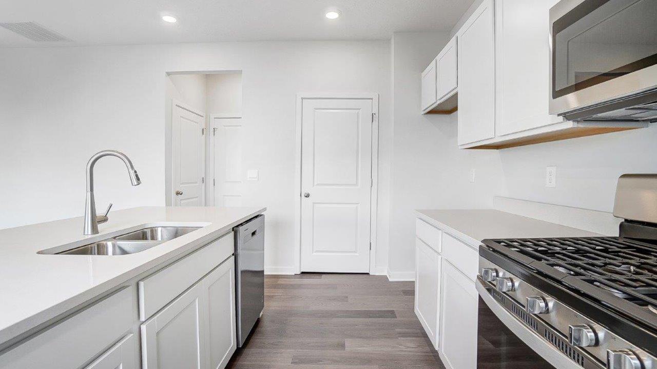 kitchen with white cabinets, built in island, stainless steel appliances, walk in pantry