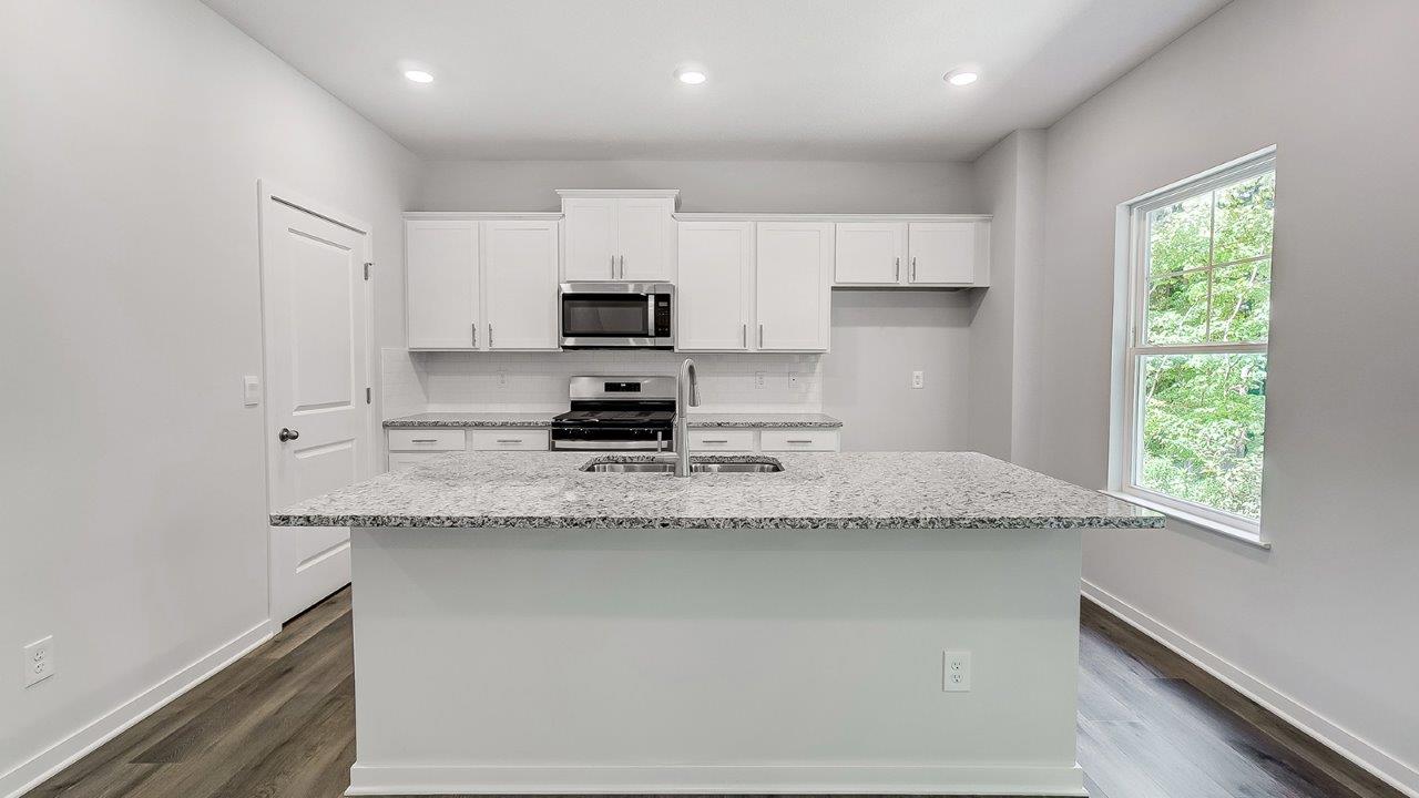 kitchen with white cabinets, built in island, single window, stainless steel appliances, walk in pantry