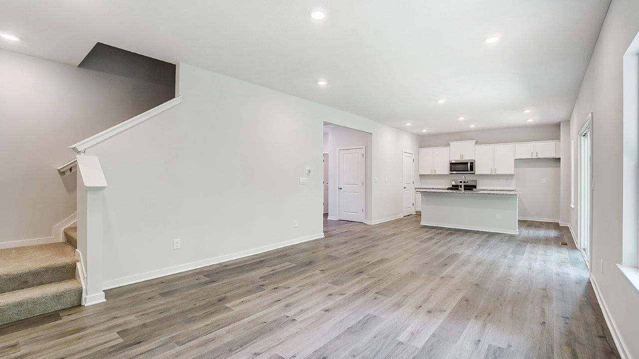 great room with tucked staircase and kitchen