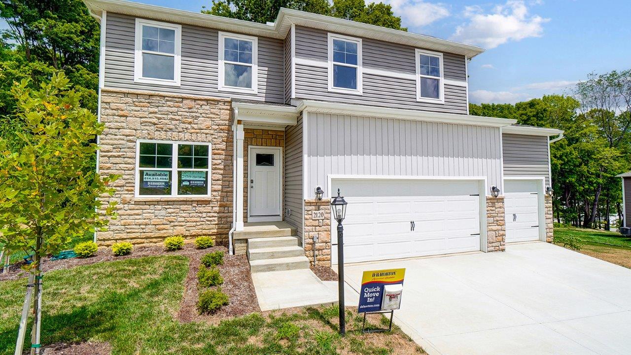 two story home with grey siding, partial stone front, covered entry and three car garage
