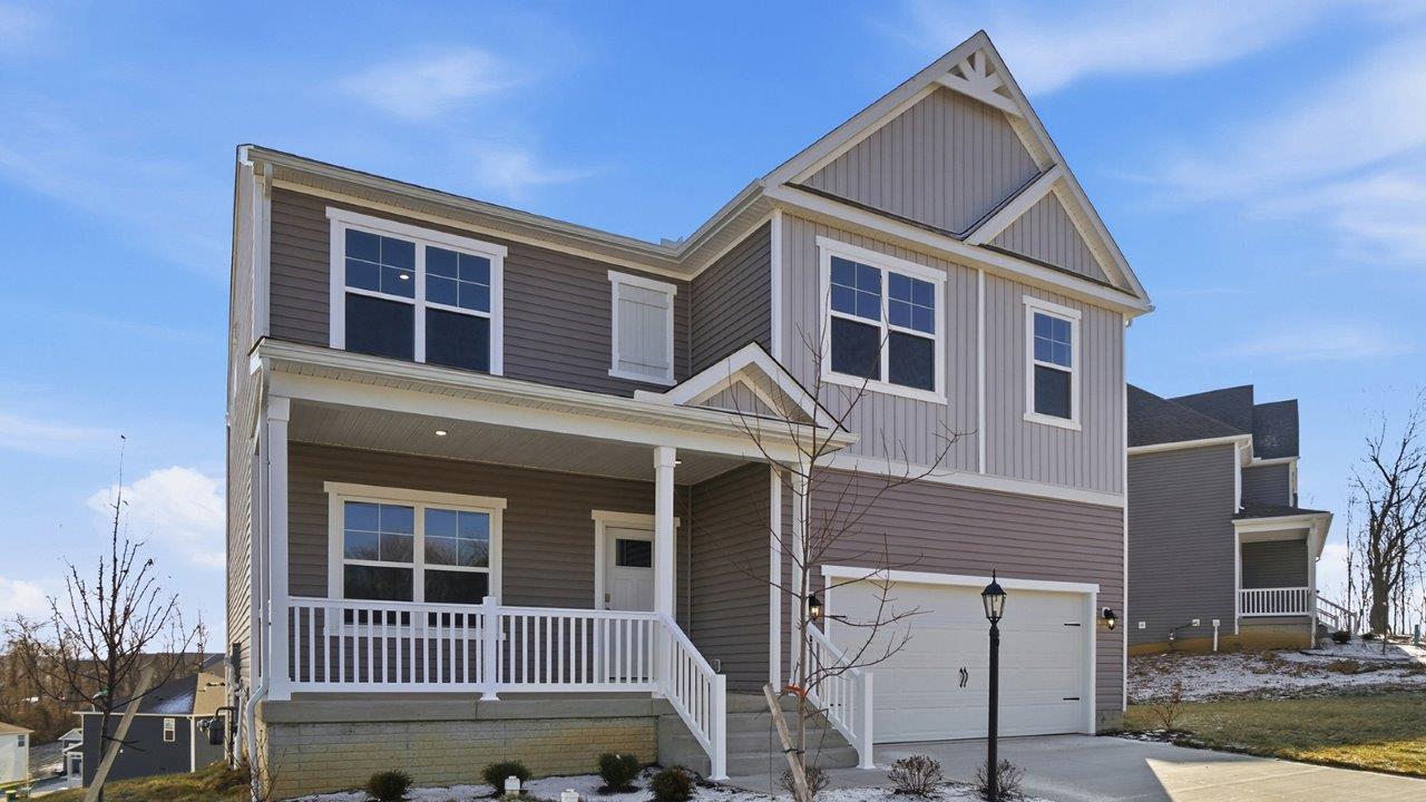 two story home with grey siding, covered front porch and two car garage