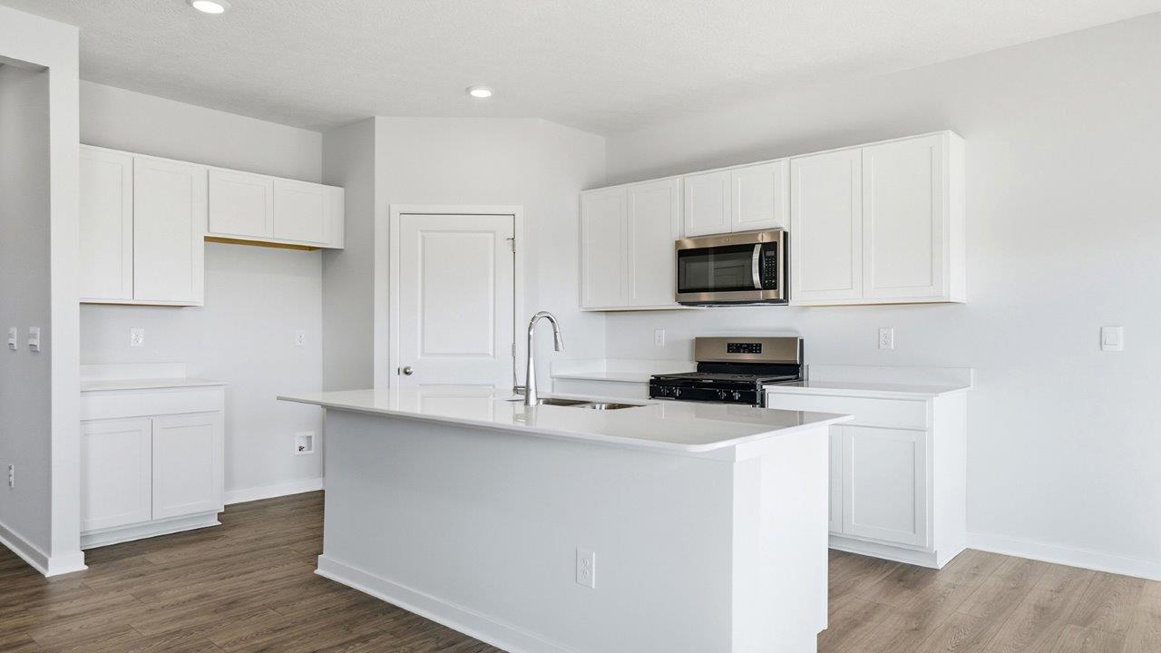 kitchen with white cabinets, built in island, corner walk in pantry, stainless steel appliances