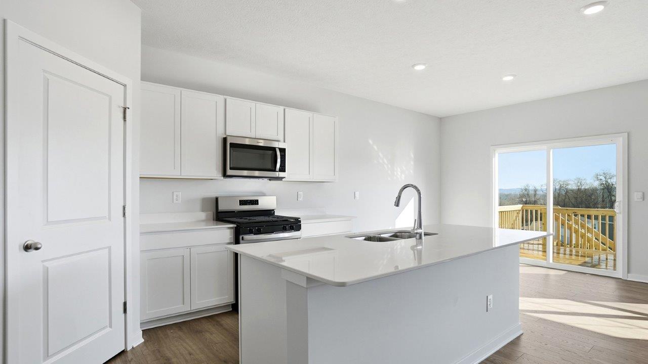 kitchen with white cabinets, built in island, walk in corner pantry, rear sliding door