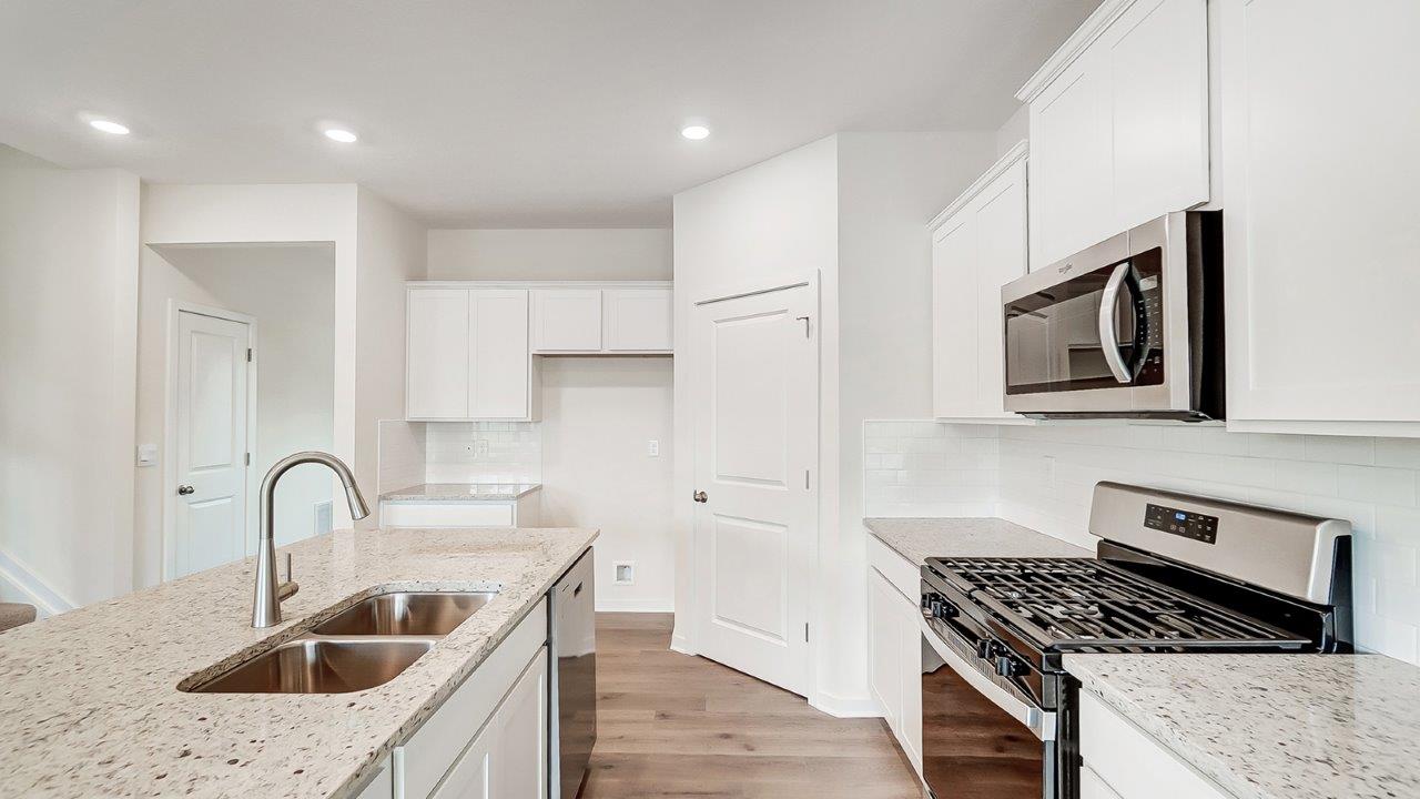 kitchen with white cabinets, stainless steel appliances, built in island and corner walk in pantry
