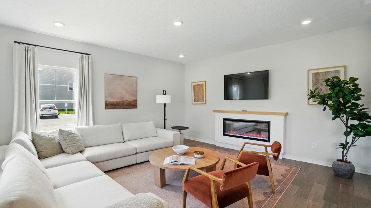 Living room featuring a white sectional against 2 windows, an orange rug and 2 red accent chairs