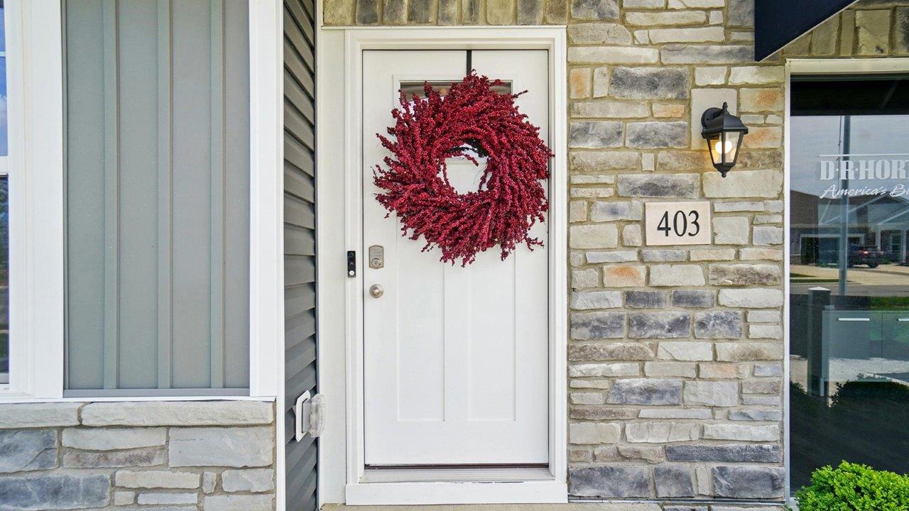 White front door of the home featuring a red wreath