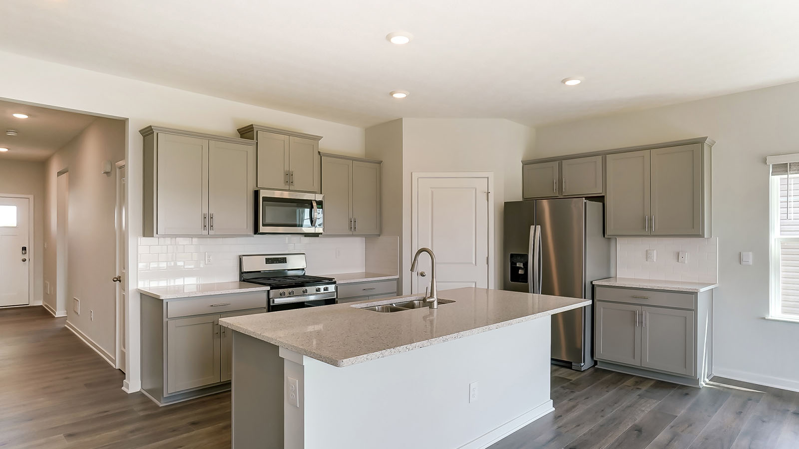 kitchen with grey cabinets, built in island, stainless steel appliances and corner walk in pantry