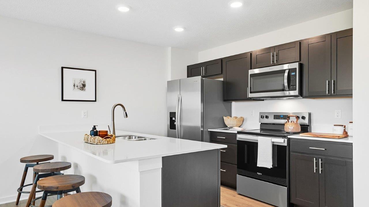 kitchen with brown cabinets, built in island with barstools, stainless steel appliances