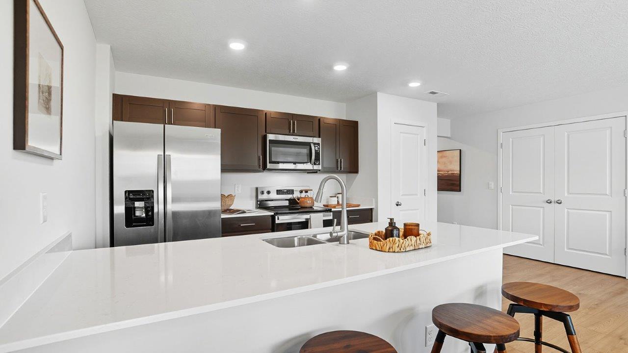 kitchen with brown cabinets, built in island with barstools, stainless steel appliances