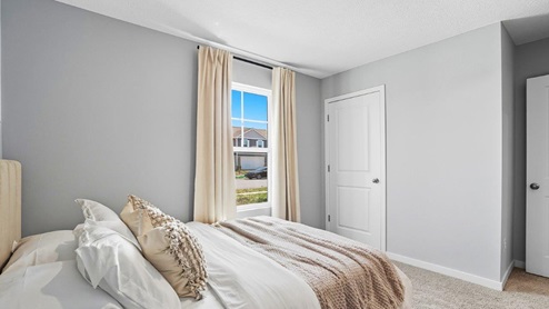 furnished second bedroom with single window and walk in closet