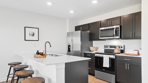 kitchen with brown cabinets, built in island with barstools, stainless steel appliances