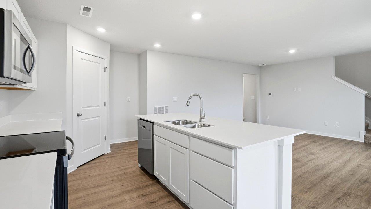 .kitchen with white cabinets, stainless steel appliances, built in island, corner walk in pantry