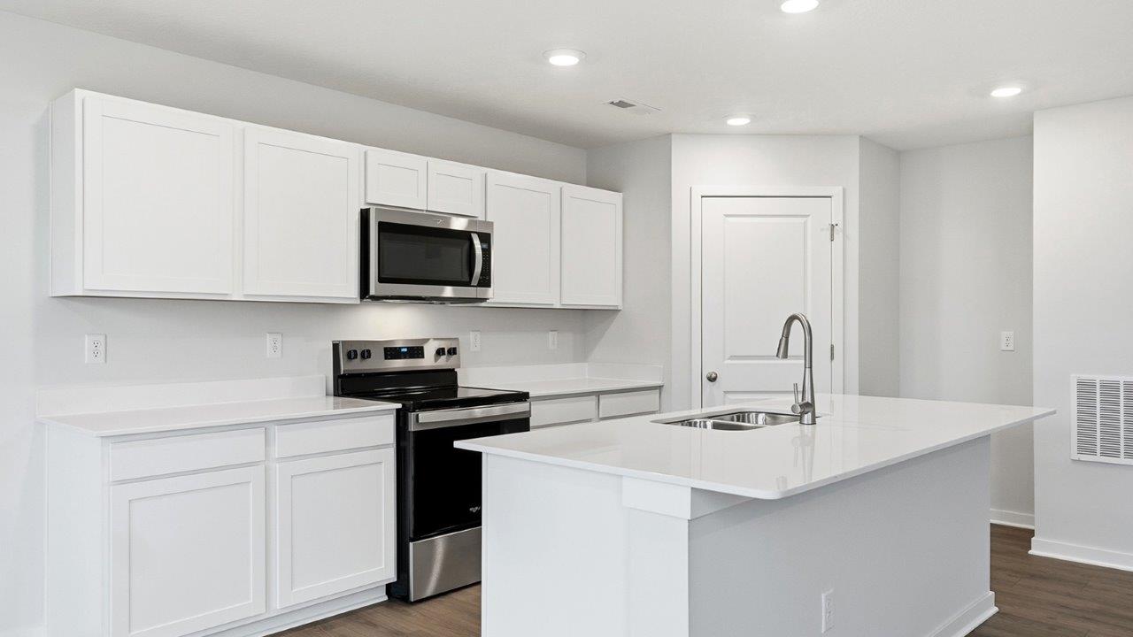 kitchen with white cabinets, built in island, stainless steel appliances and corner walk in pantry