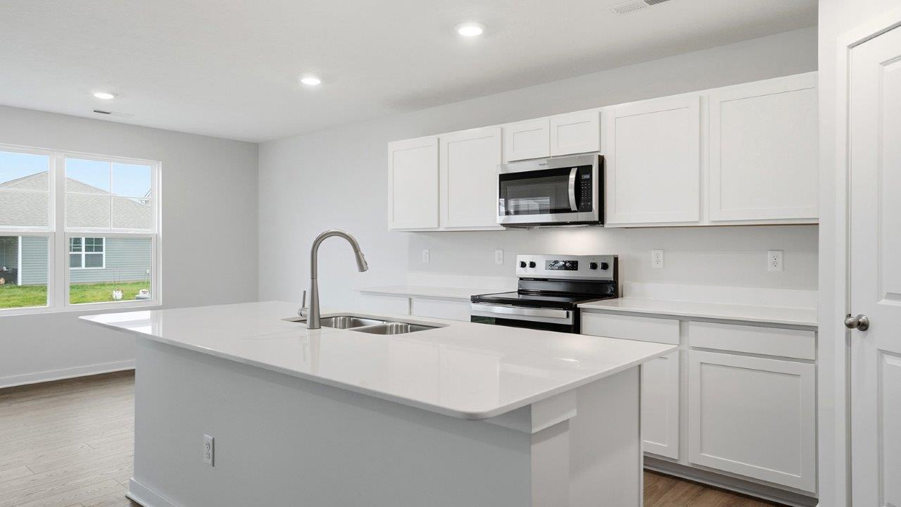 kitchen with white cabinets, stainless steel appliances, built in island, corner walk in pantry