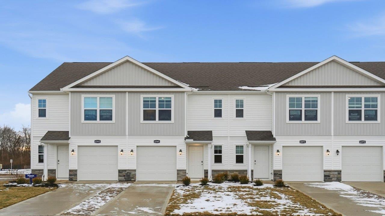 Two story townhome with grey siding, covered entry and one car garag e