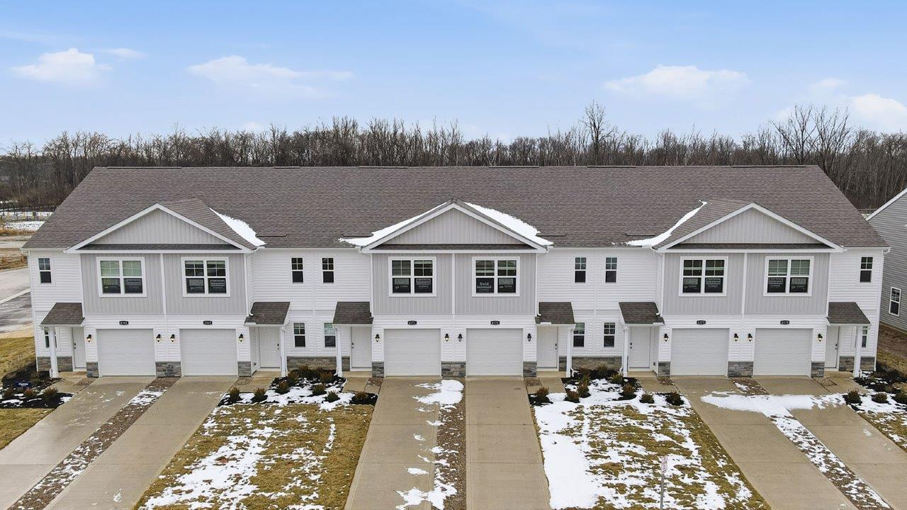 six unit townhome building with grey siding, covered entry and one car garage
