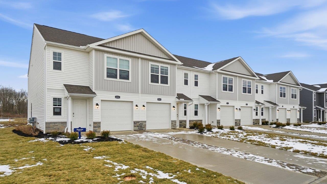 two story townhome with grey siding, covered entry and one car garage
