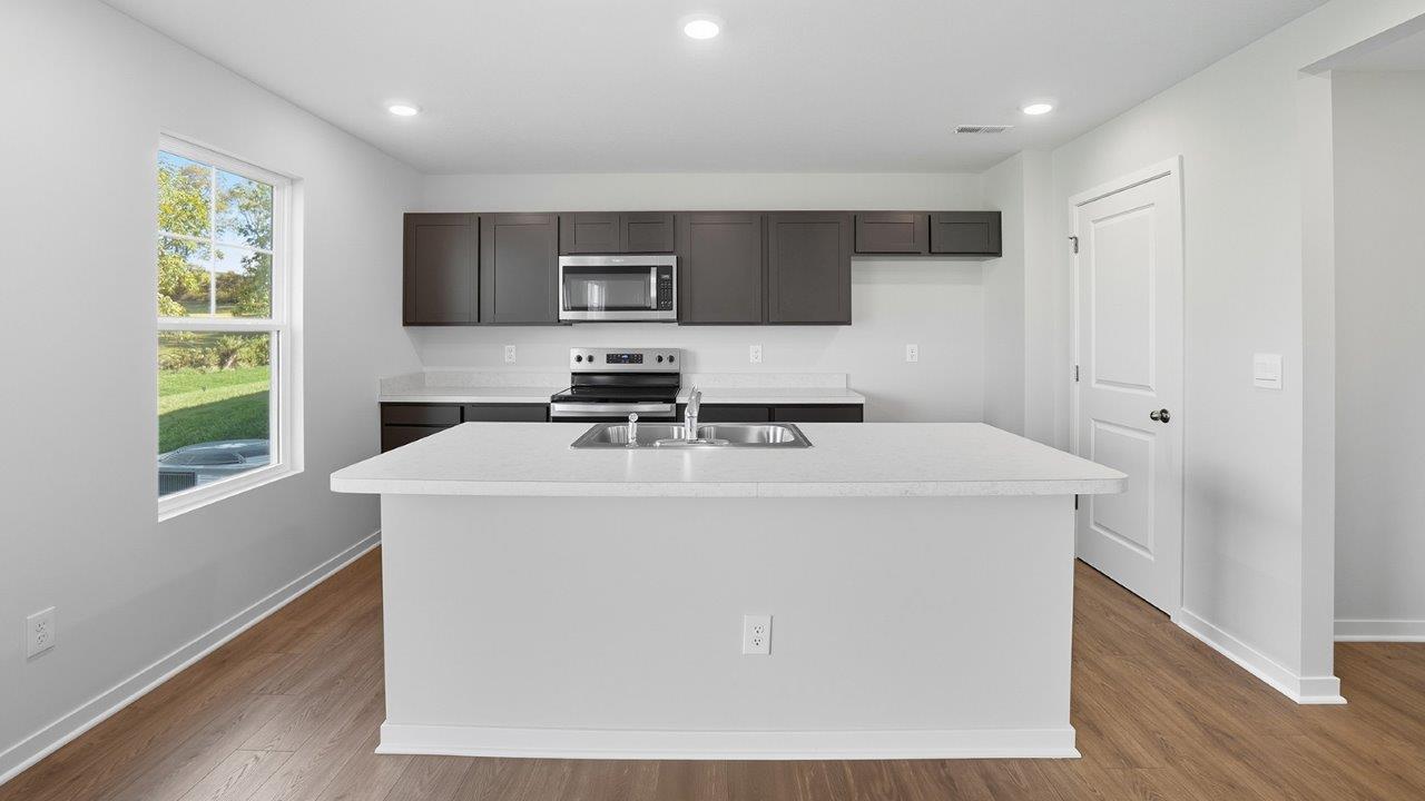 kitchen with brown cabinets, built in island, stainless steel appliances, walk in pantry, single window
