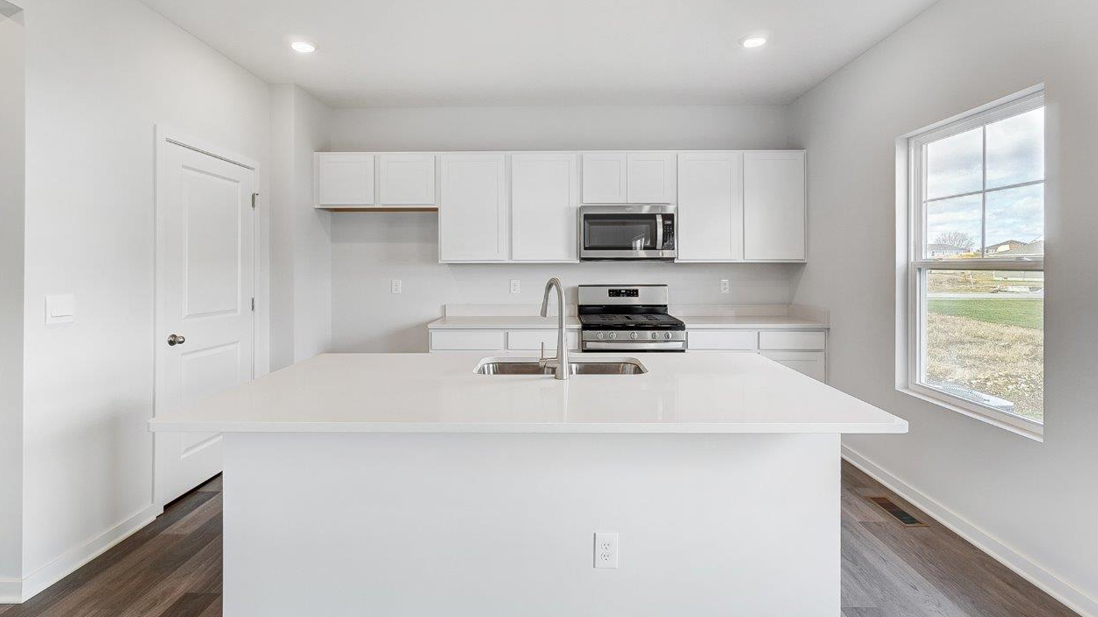 kitchen with white cabinets, built in island, stainless steel appliances, walk in pantry