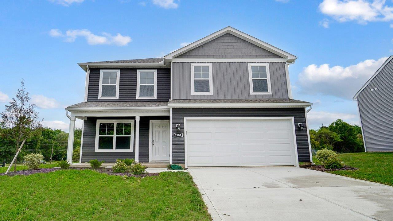 two story home with grey siding, covered front porch and two car garage