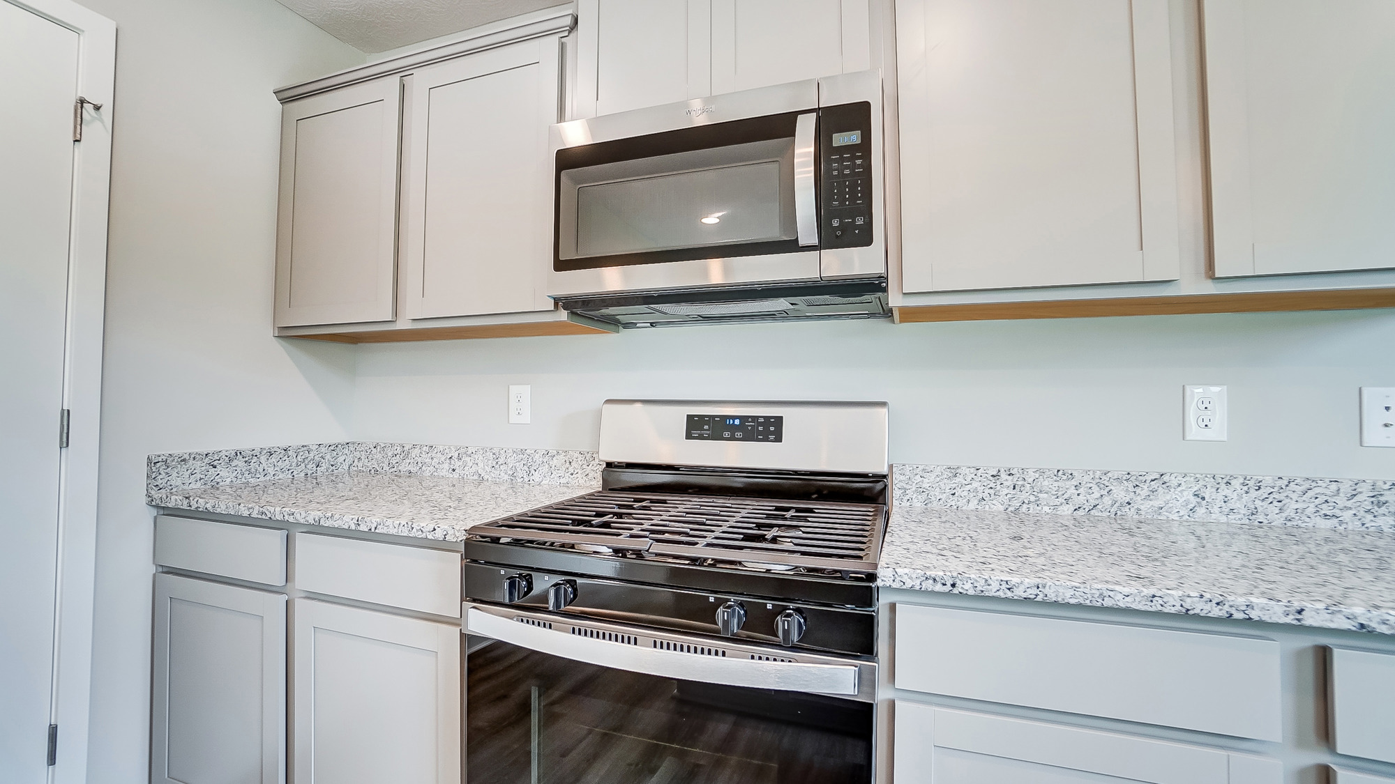 grey cabinets, hard surface counters, stainless steel microwave and range