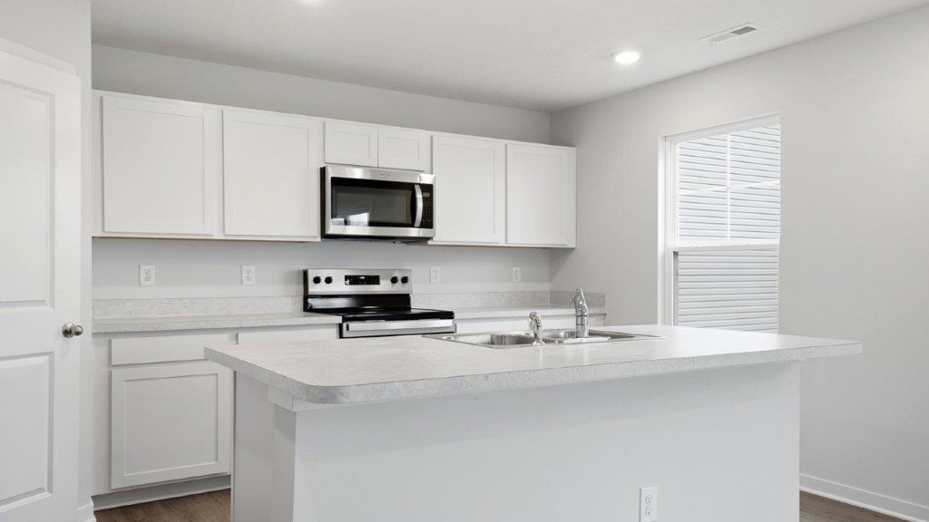 kitchen with white cabinets, built in island, stainless steel appliances, single window