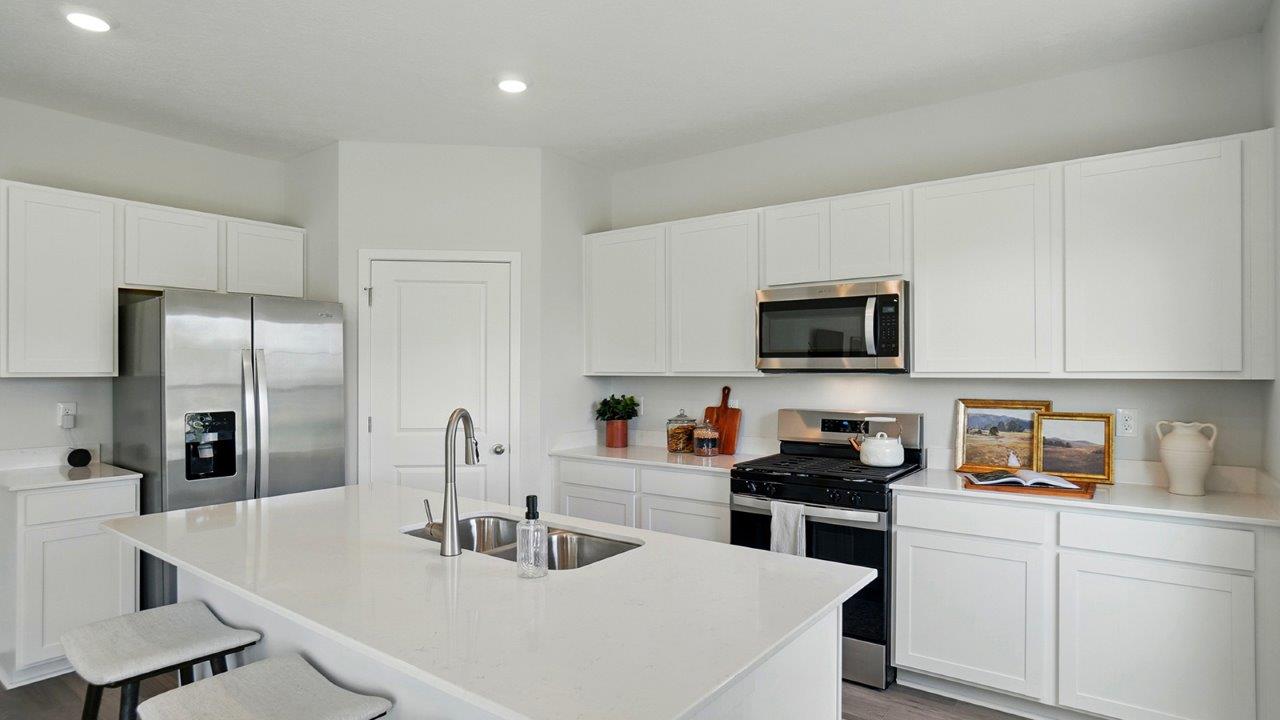 kitchen with white cabinets, hard surface counters, stainless steel appliances, corner walk in pantry