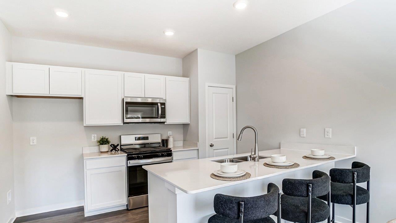 kitchen with white cabinets, stainless steel appliances and barstools