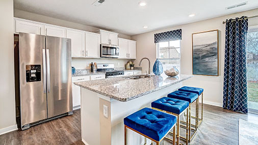 kitchen with white cabinets, built in island with barstools, stainless steel appliances