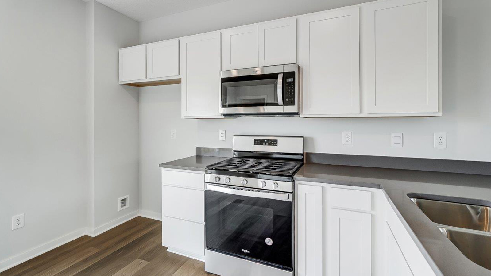 kitchen with peninsula counter, white cabinets, stainless microwave and range