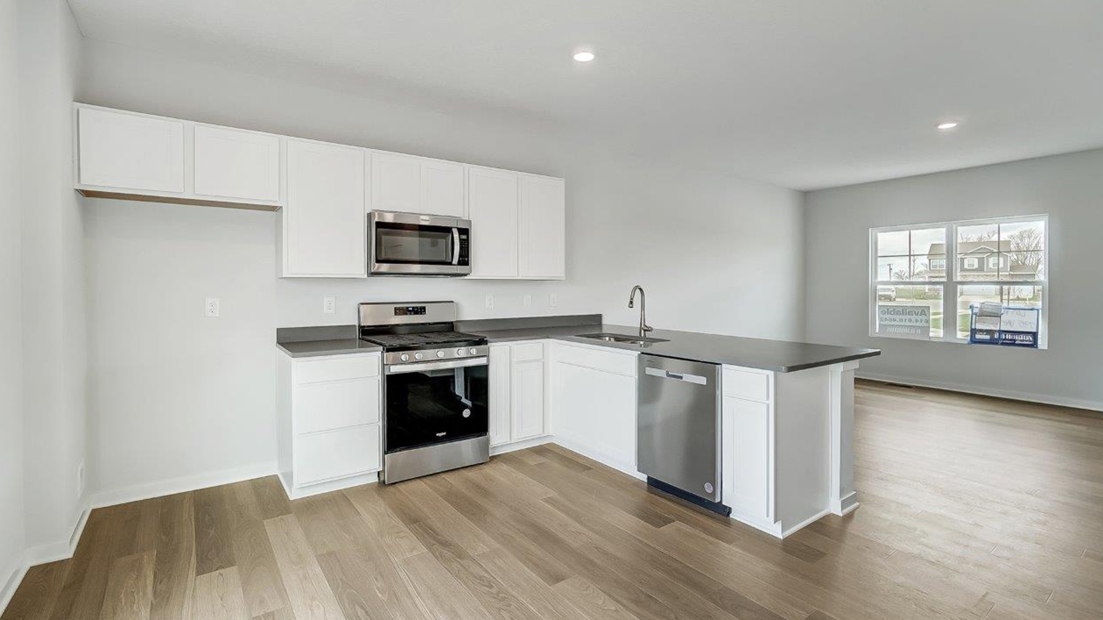 kitchen with peninsula counter, white cabinets, stainless appliances, great room