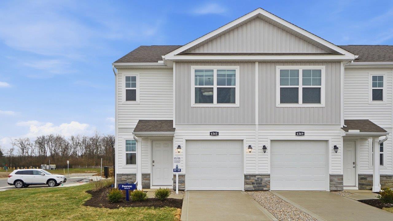 Two story townhome with grey siding, covered entry and one car garag e