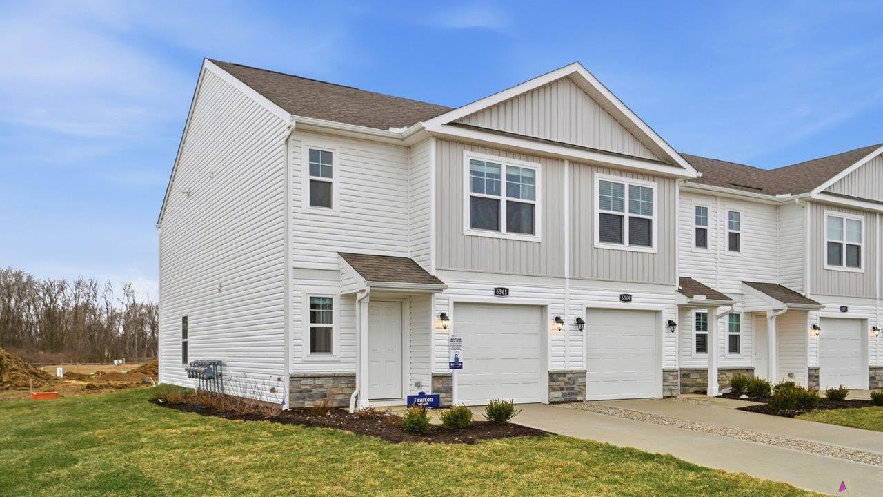 Two story townhome with grey siding, covered entry and one car garag e