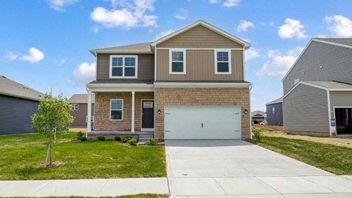 two story home with tan siding, partial stone, covered entry, two car garage