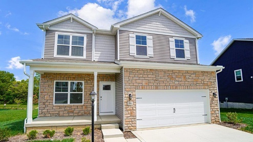 two story home with grey siding, partial stone front, covered front porch and two car garage angle