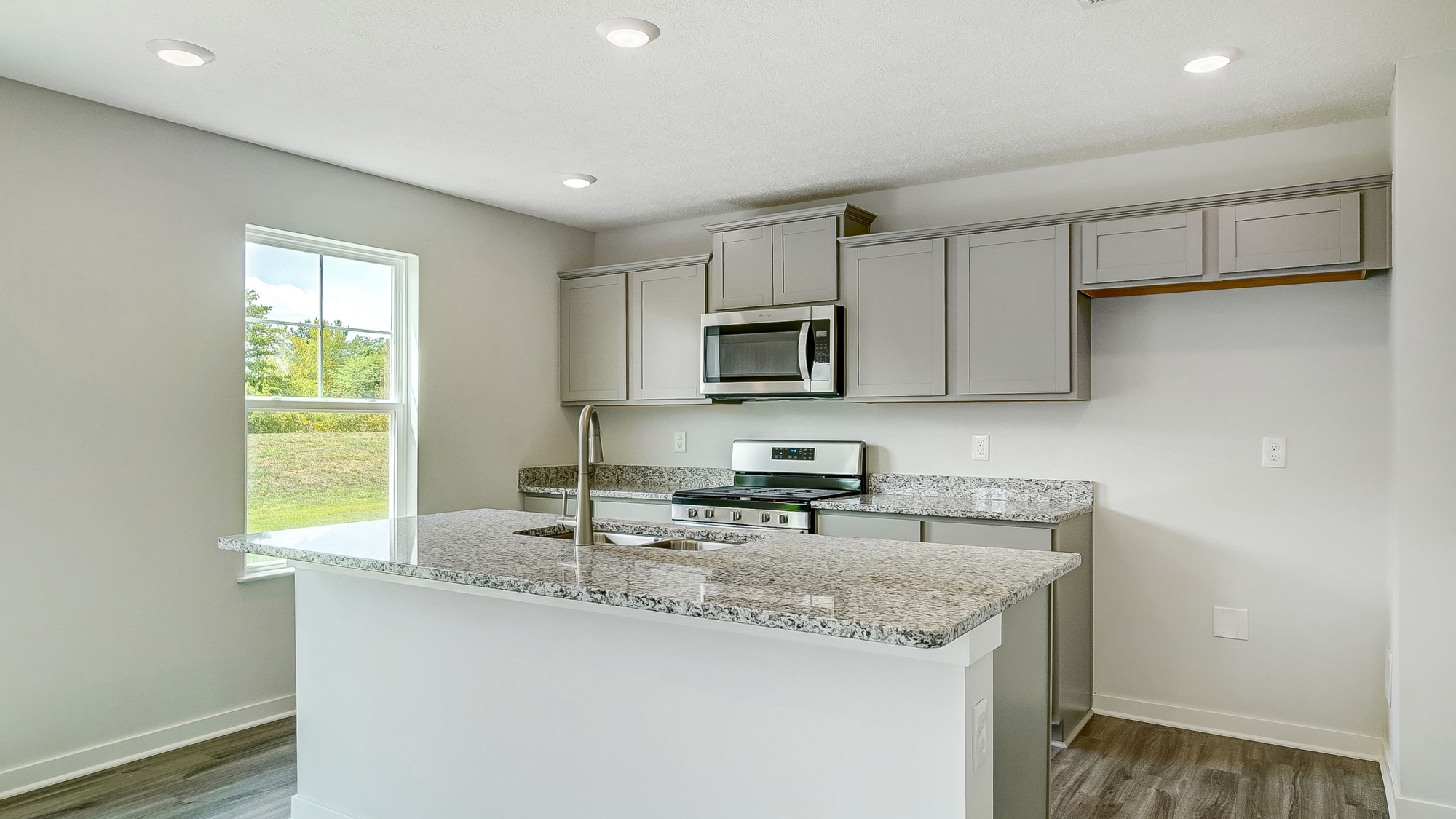 kitchen with built in island, single window, grey cabinets, stainless steel appliances