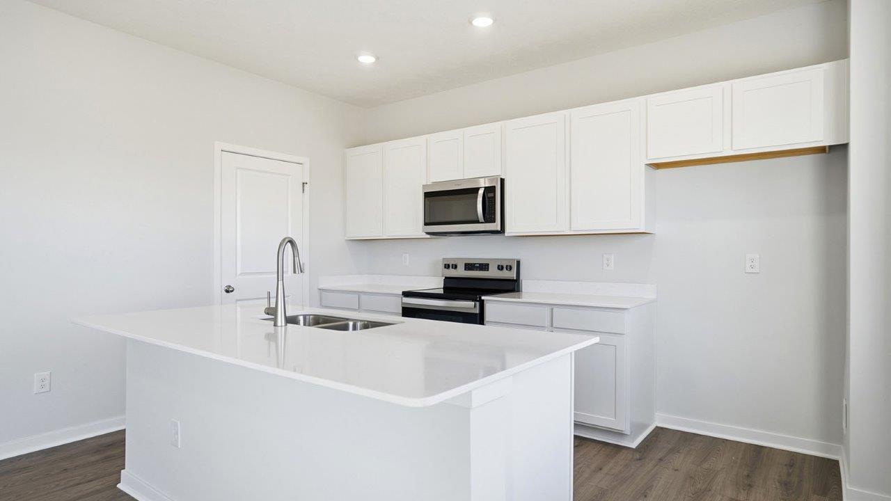 kitchen with white cabinets, built in island, stainless steel appliances, walk in pantry