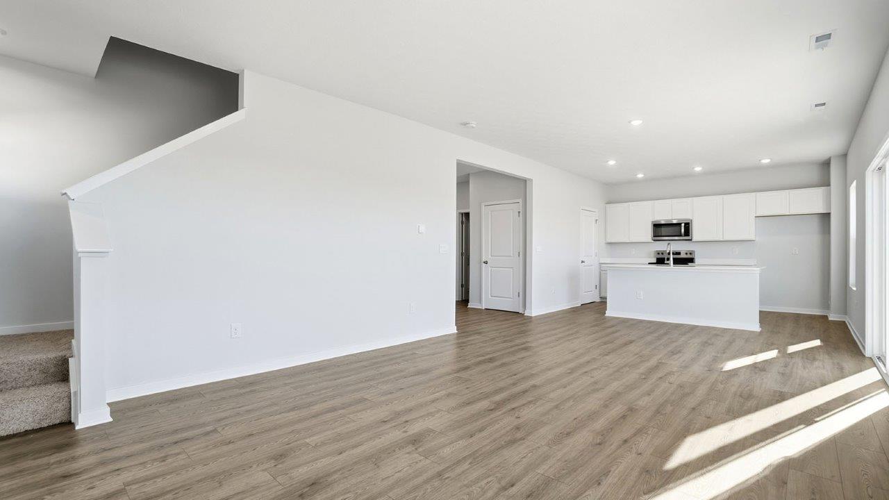 great room with tucked staircase and kitchen