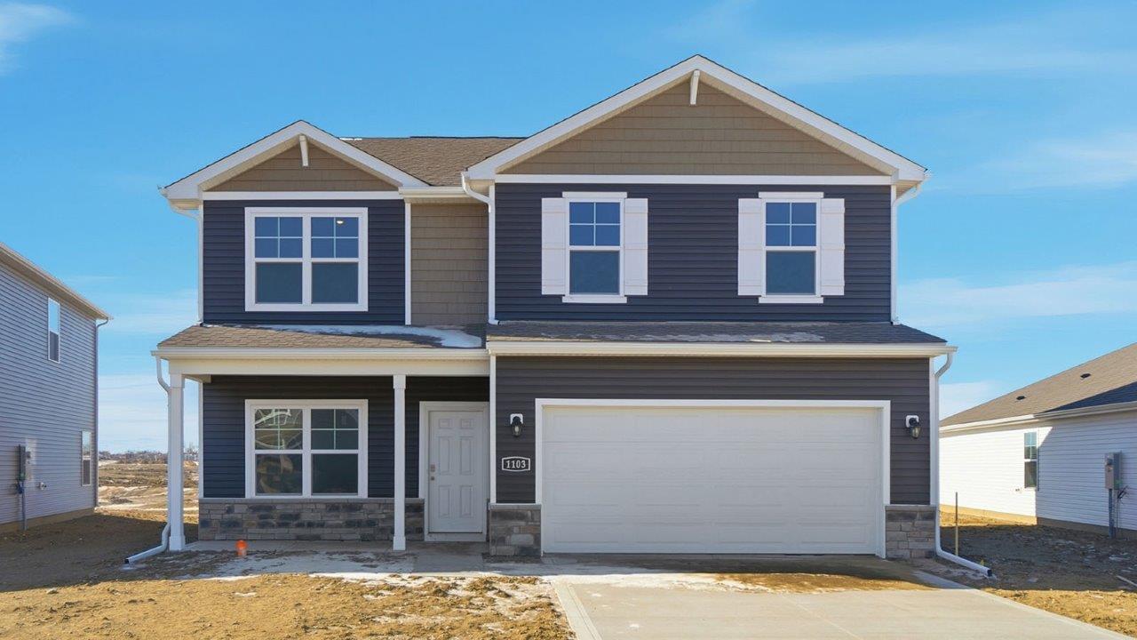 two story home with grey siding, stone water table, covered front porch and two car garage