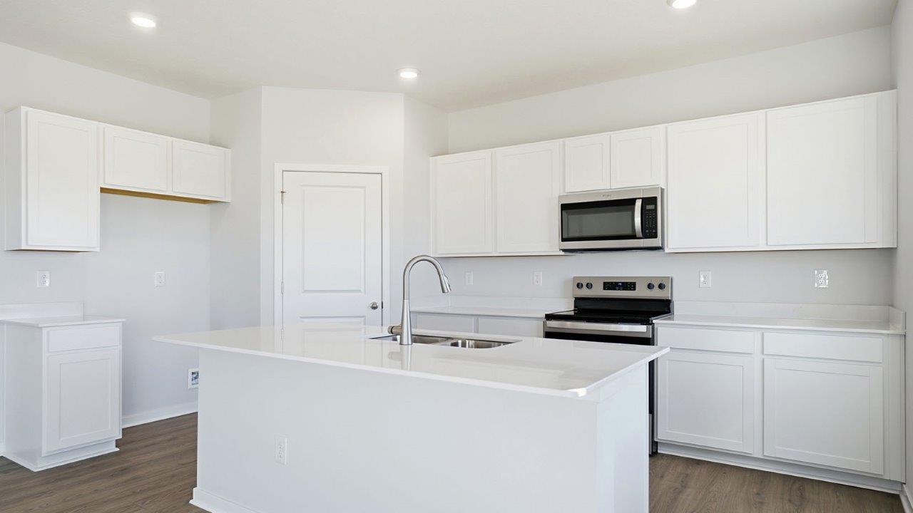 kitchen with white cabinets, built in island, hard surface counters, stainless steel appliances and walk in pantry