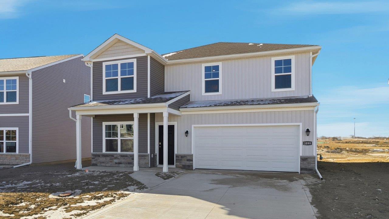 two story home with grey siding, stone water table, covered front porch and two car garage