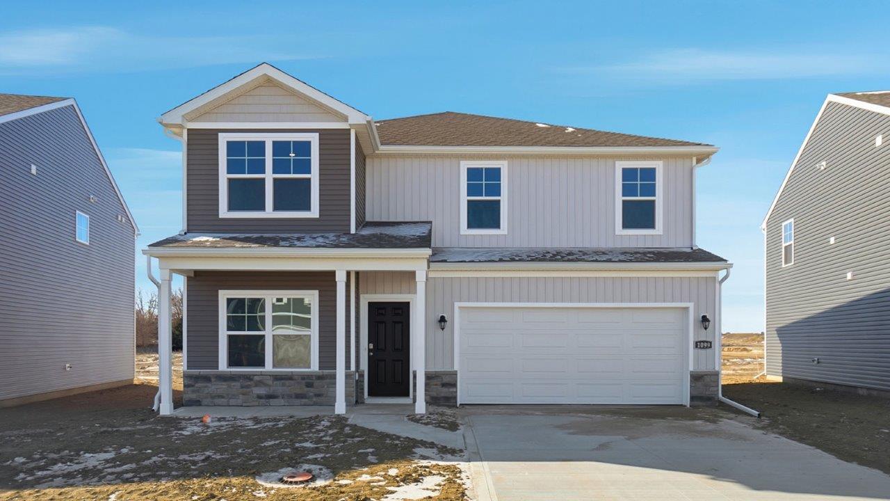 two story home with grey siding, stone water table, covered front porch and two car garage