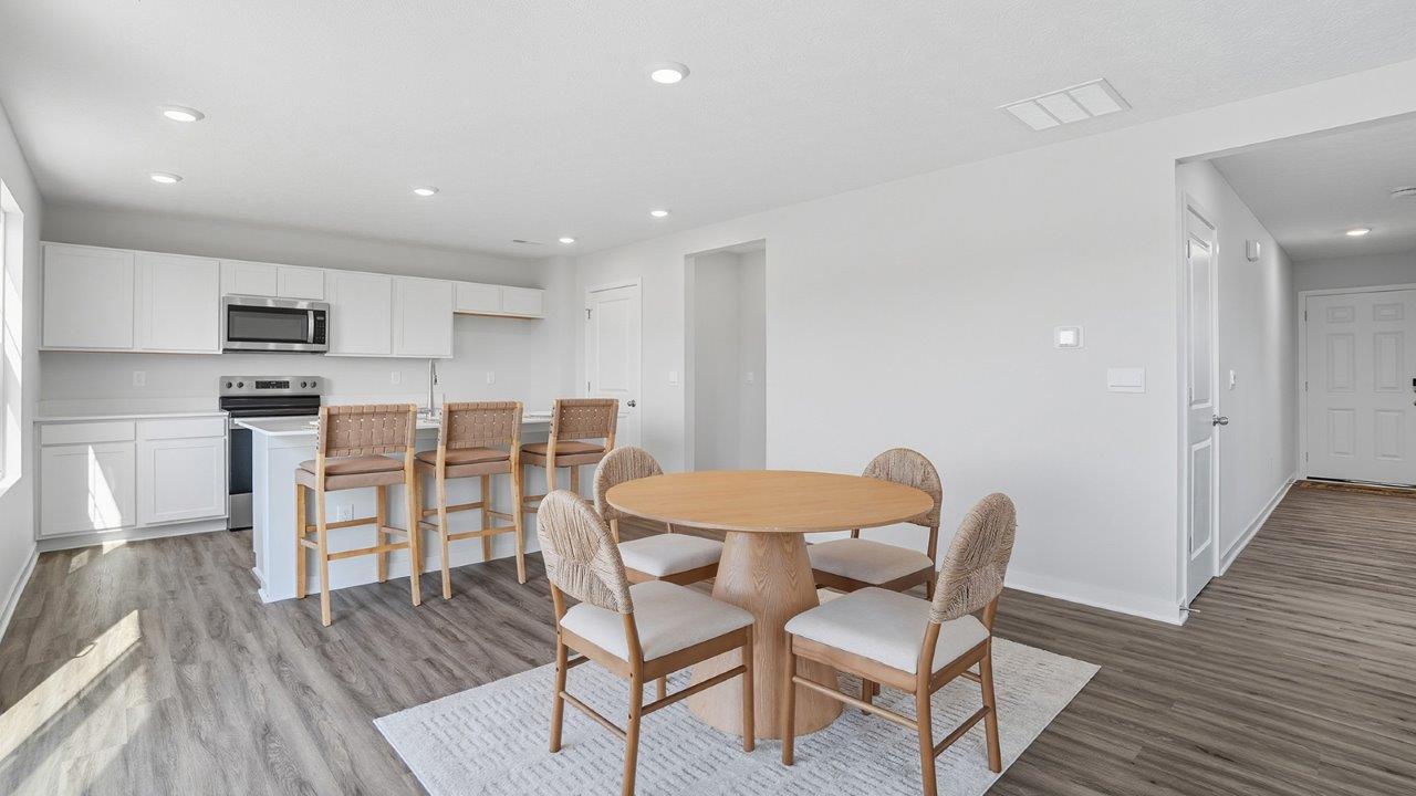 round dining table with chairs, kitchen with island and barstools, front hallway