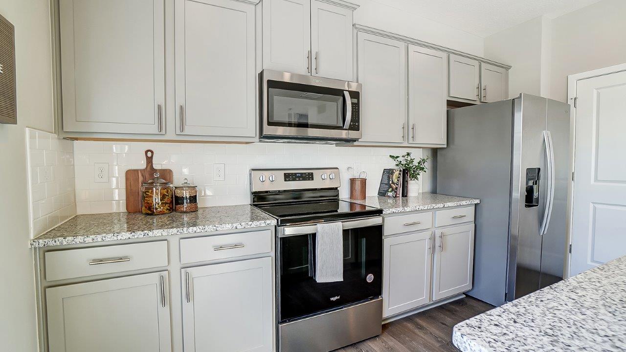 grey kitchen cabinets, hard surface counters, stainless steel appliances